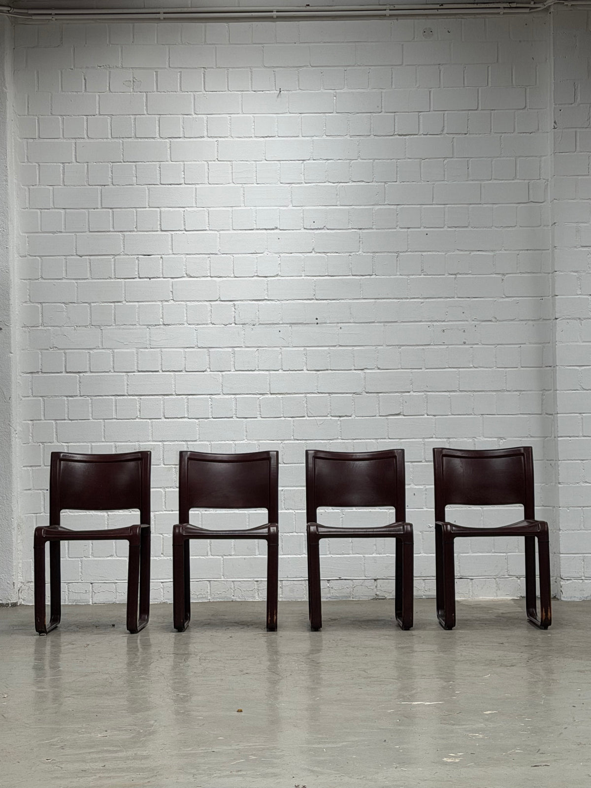 A Set of 4 Matteo Grassi - Sinistra - chairs in Burgundi leather designed by Tito Agnolio